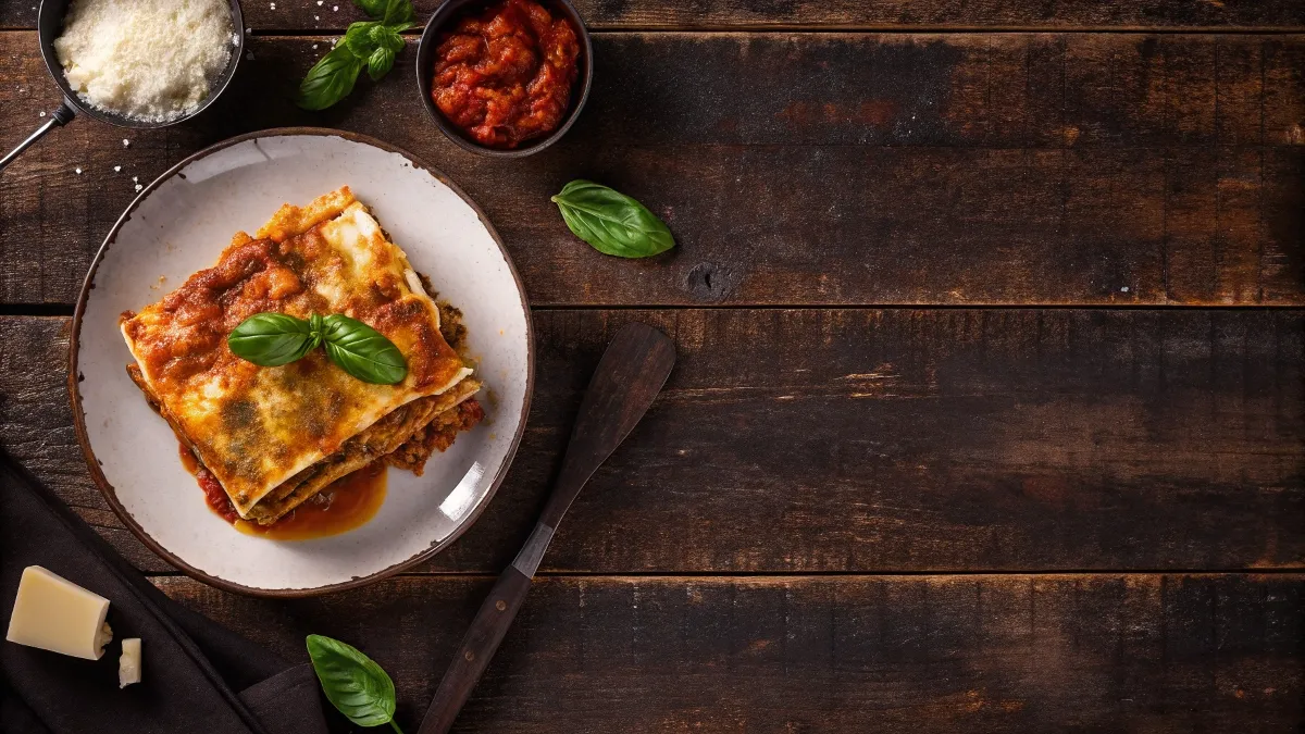 A slice of lasagna showing layers of ricotta or cottage cheese, pasta, and tomato sauce with fresh basil.