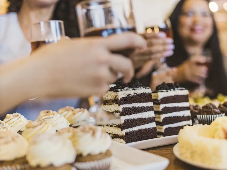 A table of assorted chocolate cakes with friends celebrating National Chocolate Cake Day.