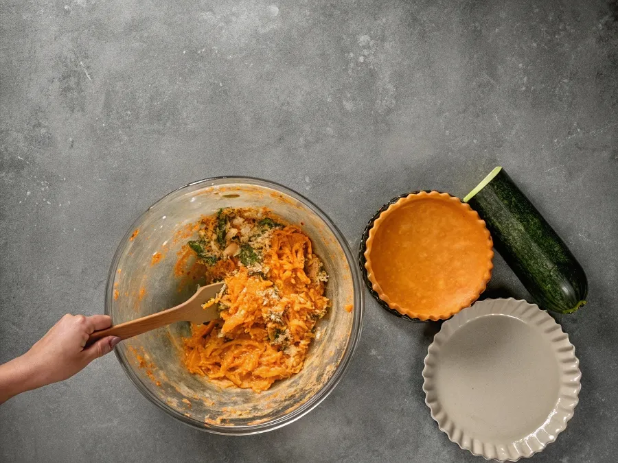 Mixing grated zucchini, eggs, and cheese for zucchini pie filling in a bowl