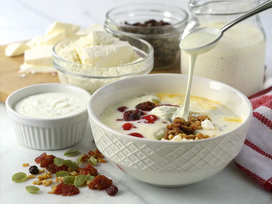 Bowl of creamy soup topped with a swirl of cream and fresh herbs.