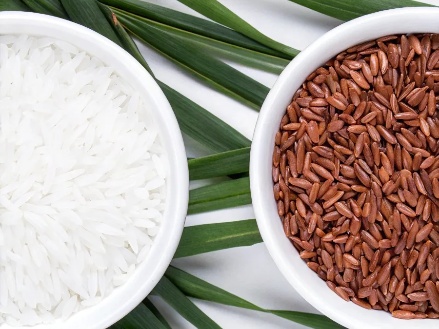 ide-by-side comparison of bowls with white rice and brown rice, showcasing their texture differences.